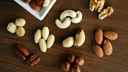 Close-up of various nuts on a wooden table, showcasing healthy snacking options.