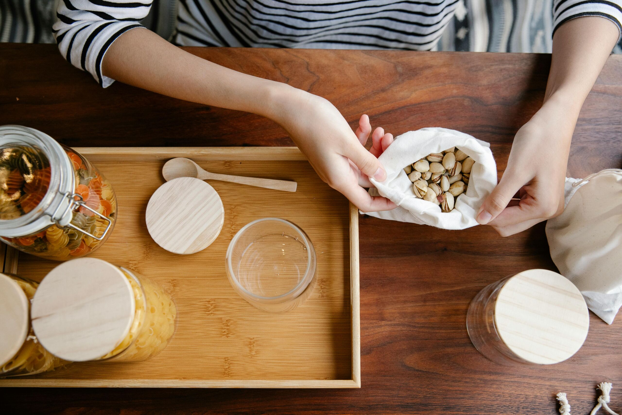 Eco-conscious kitchen scene showcasing pistachios in reuseable packaging and glass jars, emphasizing sustainability.