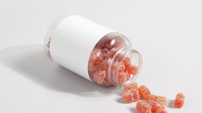 Close-up of gummy vitamins spilled from a clear bottle on a white surface