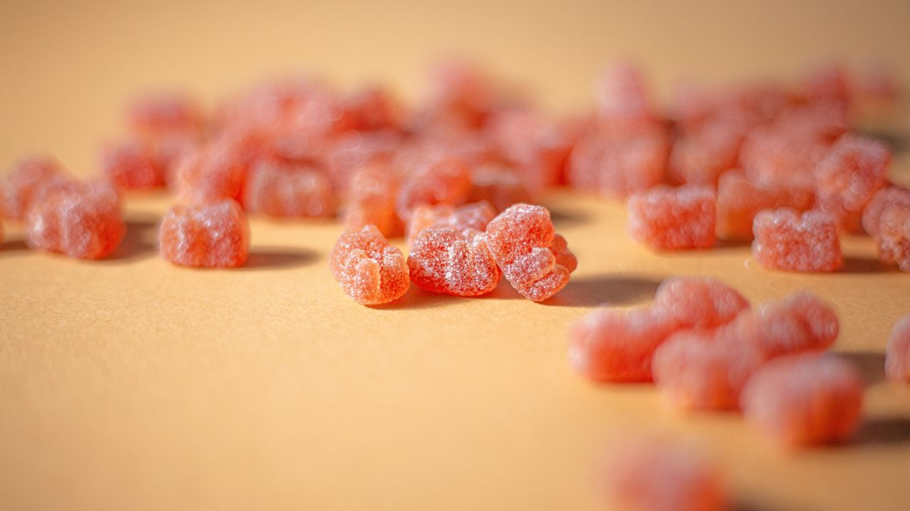 Macro shot of sugar-coated gummy candies on a plain surface in bright light.