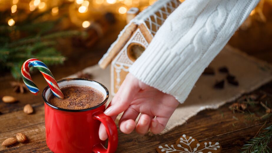 Warm and inviting winter scene with hot chocolate and gingerbread house.